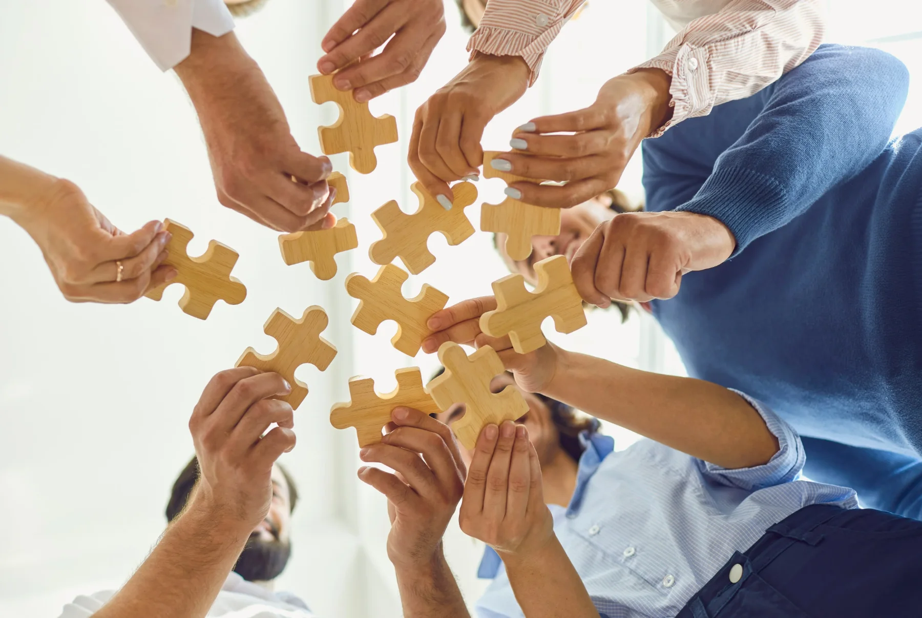 Several people fitting puzzle pieces together, illustrating a collaborative and personalised therapeutic approach