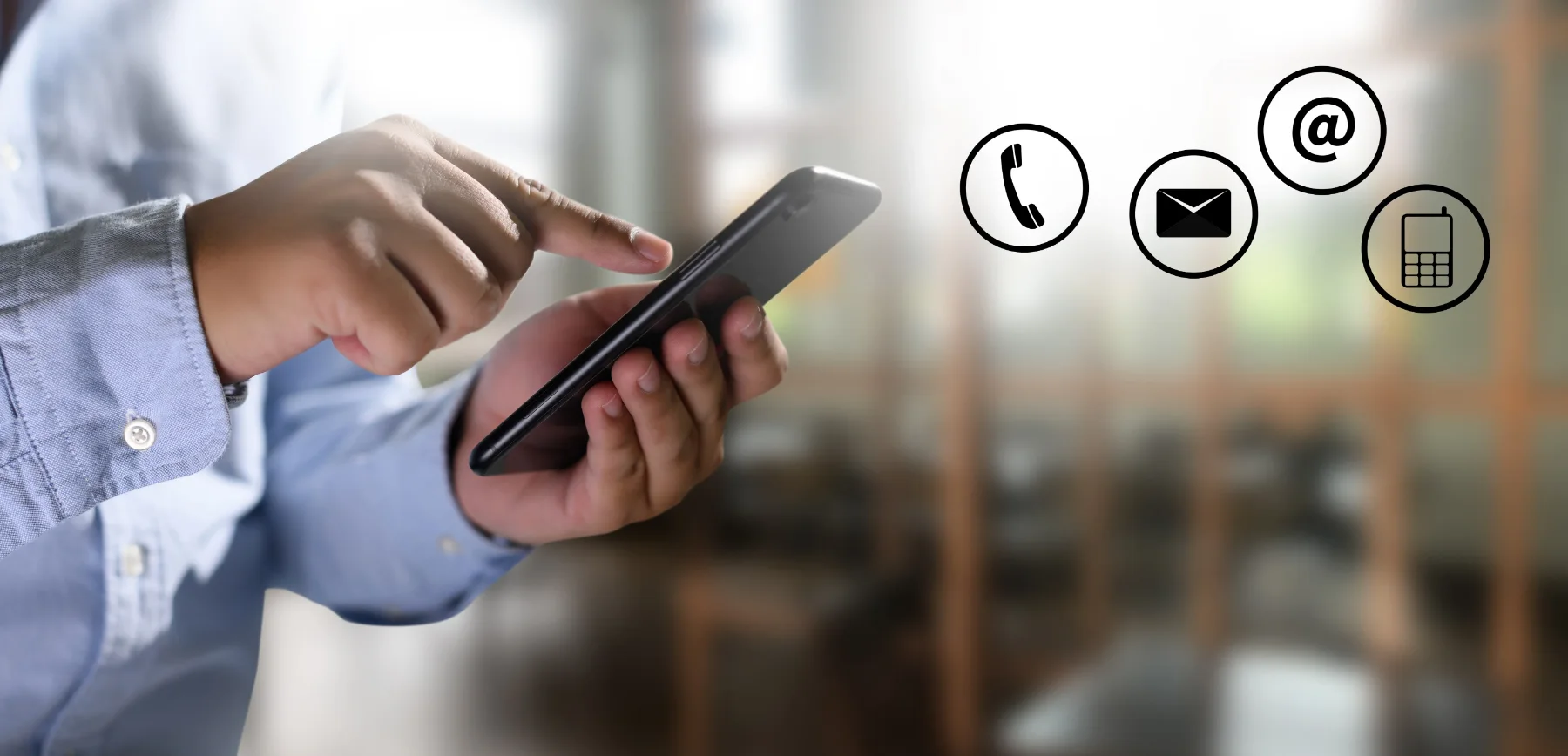 A hand holding a mobile phone beside phone, email and message icons, representing ways to contact the practice
