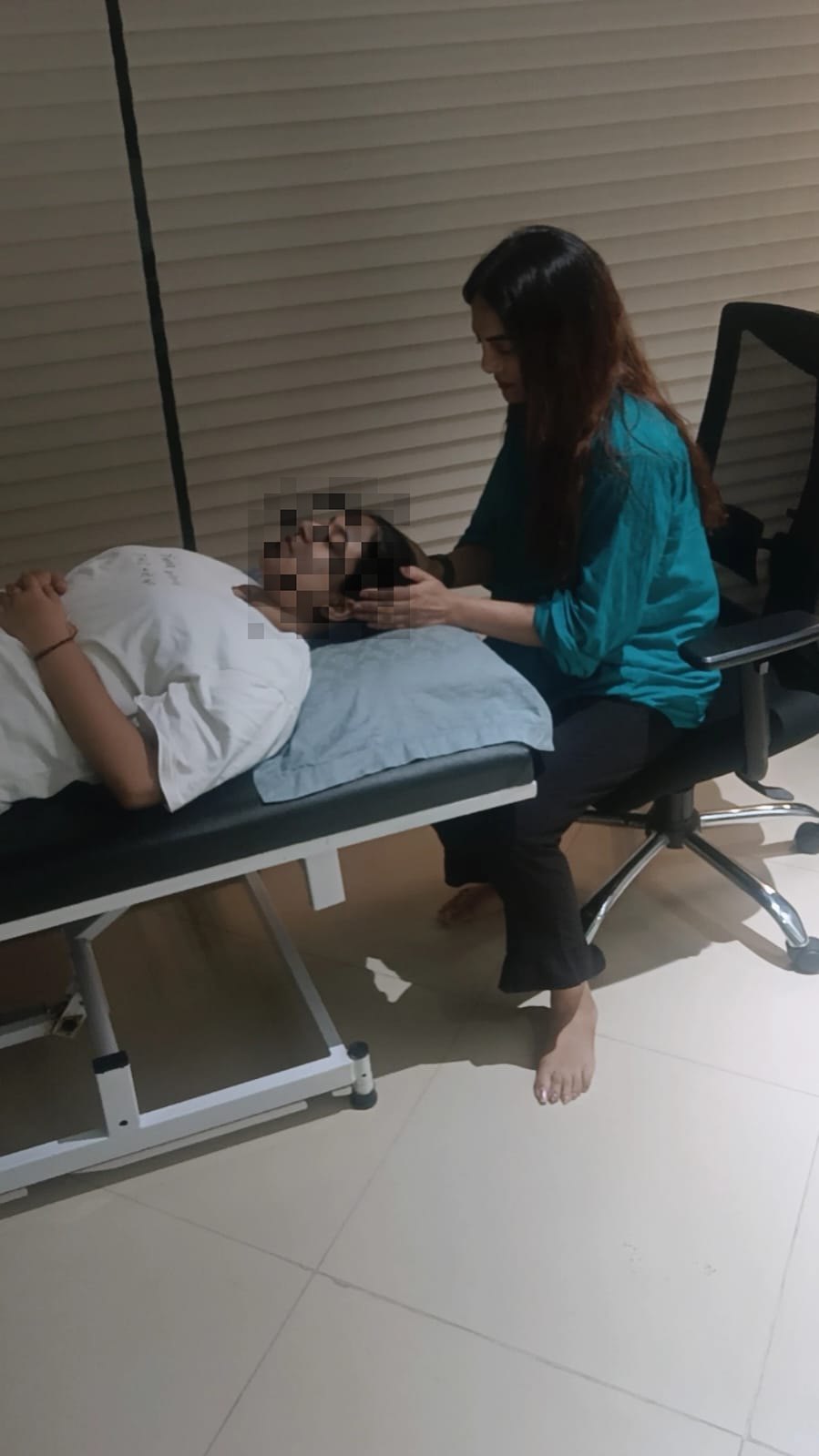 A hypnotherapy session in progress, with the practitioner seated beside a client resting comfortably